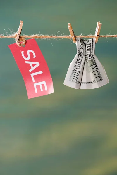 Знак продажи и долларовая купюра на бельевой веревке — стоковое фото