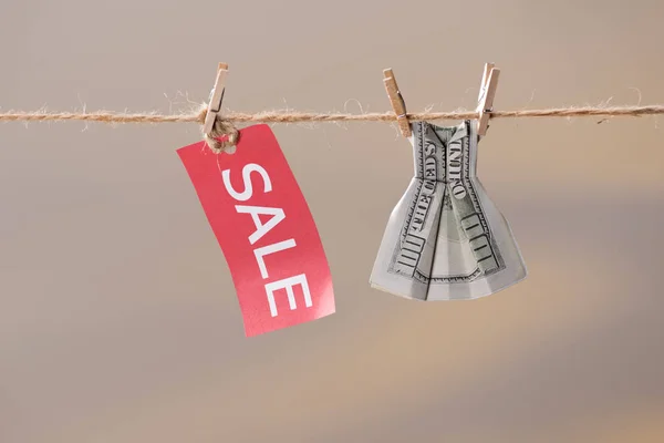 Sale sign and dollar banknote on clothesline — Stock Photo, Image