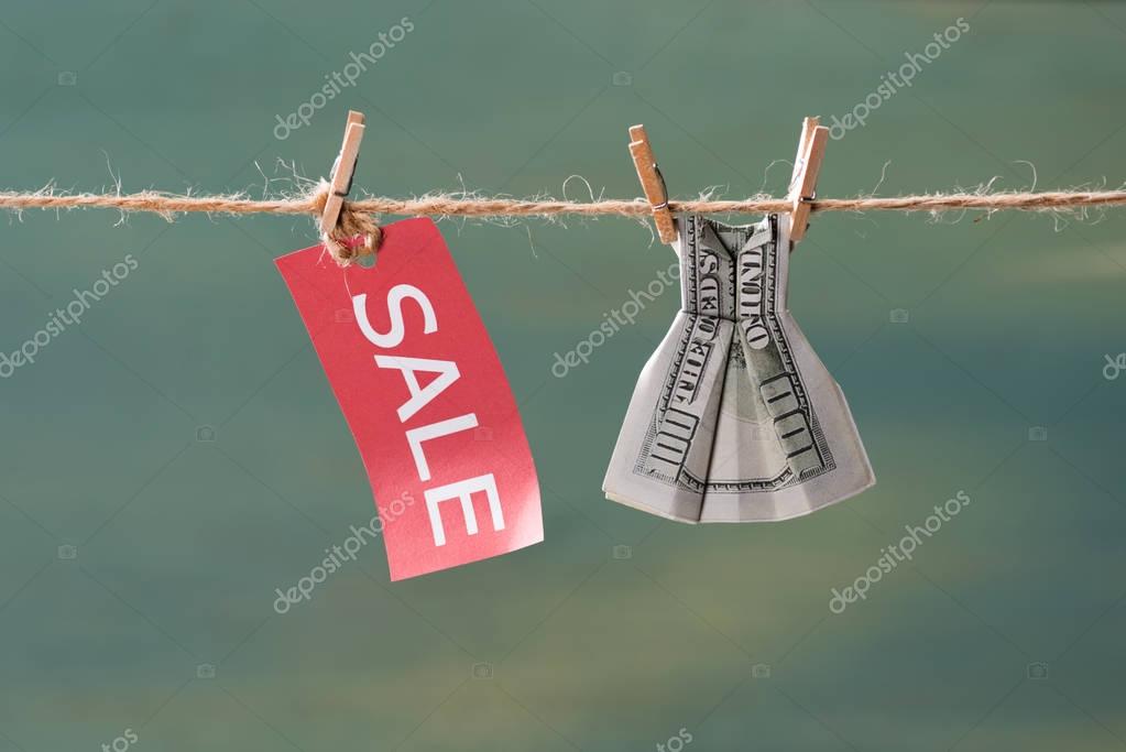 Sale sign and one hundred us dollar banknote on clothesline, offer sale concept