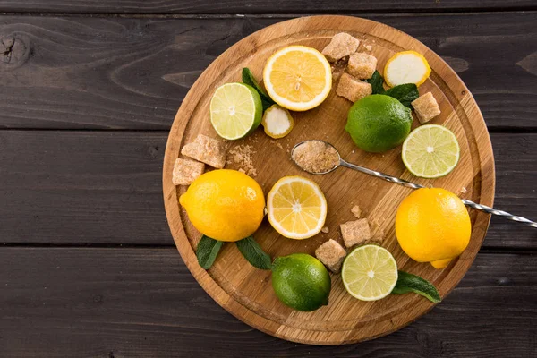 Lemons and limes with brown sugar — Stock Photo, Image