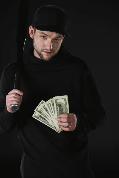 Robber in zoodie with baseball bat and money — Stock Photo, Image