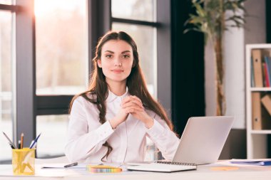 young smiling businesswoman sitting at table clipart