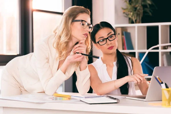 Jonge multi-etnische vrouwelijke ondernemers kijken naar laptop — Stockfoto