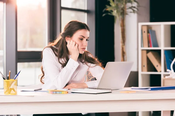 Podnikatelka, zatímco sedí v kanceláři při pohledu na notebook — Stock fotografie