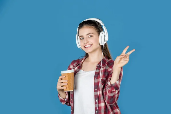 Tiener meisje in hoofdtelefoon met koffie — Stockfoto