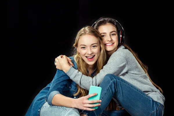 Ragazze che utilizzano smartphone e abbracciano Fotografia Stock