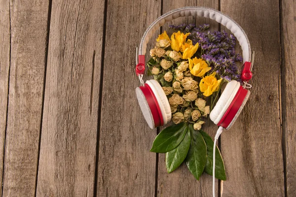 Auriculares y flores en la mesa - foto de stock