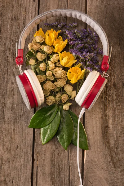 Auriculares y flores en la mesa - foto de stock