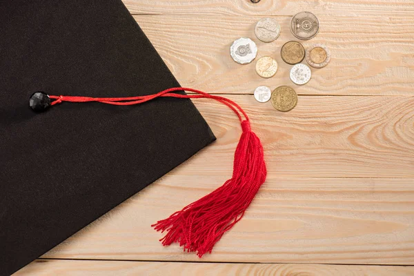 Graduation mortarboard and coins — Stock Photo