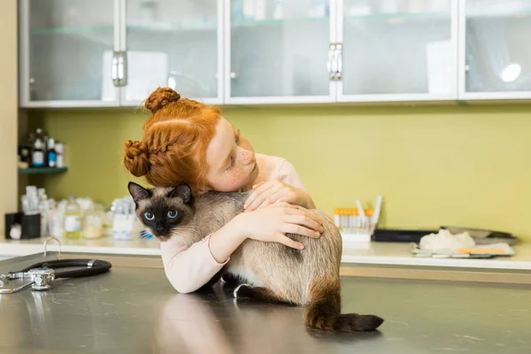 Ragazza abbracciare il suo gatto in clinica veterinaria — Foto stock