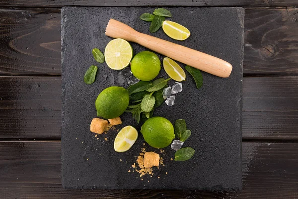 Tranches de citron vert avec sucre et pressoir en bois — Photo de stock