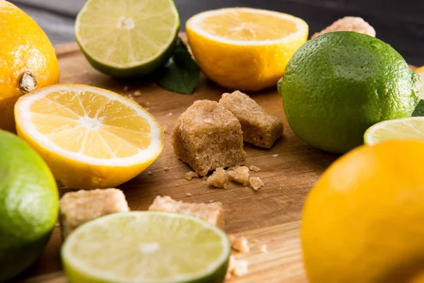 Lemons and limes with brown sugar — Stock Photo