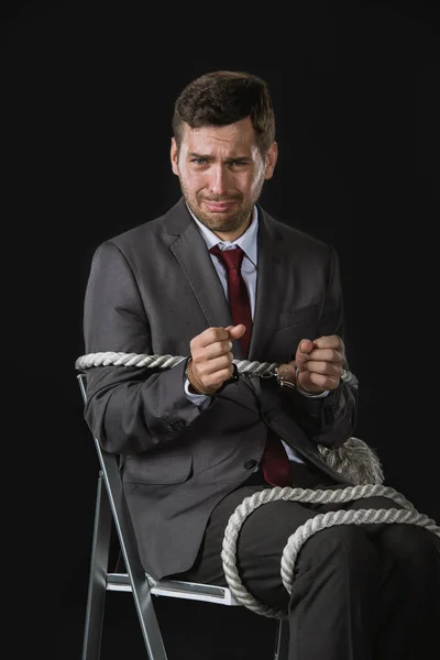 Young businessman roped on to chair — Stock Photo