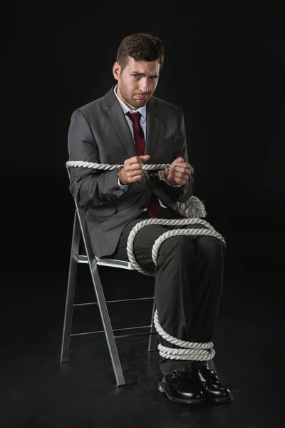 Young businessman roped on to chair — Stock Photo