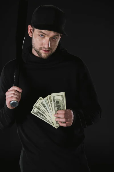 Robber in zoodie with baseball bat and money — Stock Photo