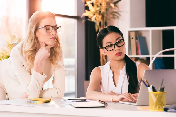 Young multiethnic businesswomen looking at laptop — Stock Photo