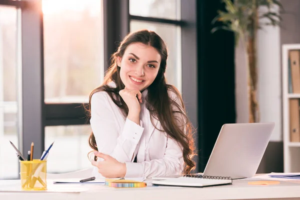 Young smiling businesswoman sitting at table — Stock Photo