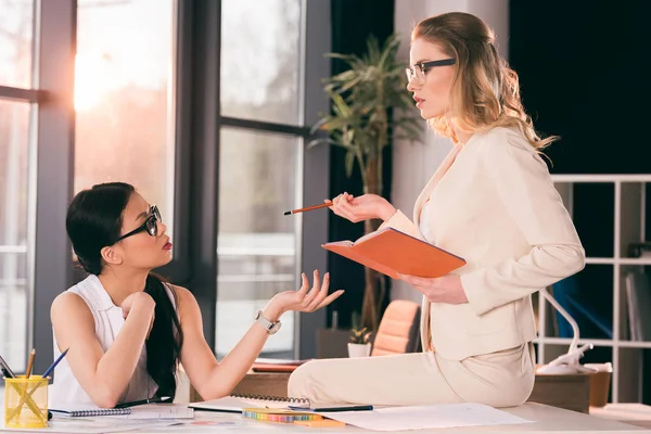 Мультиэтнические бизнесвумен в формальной одежде говорить в офисе — стоковое фото