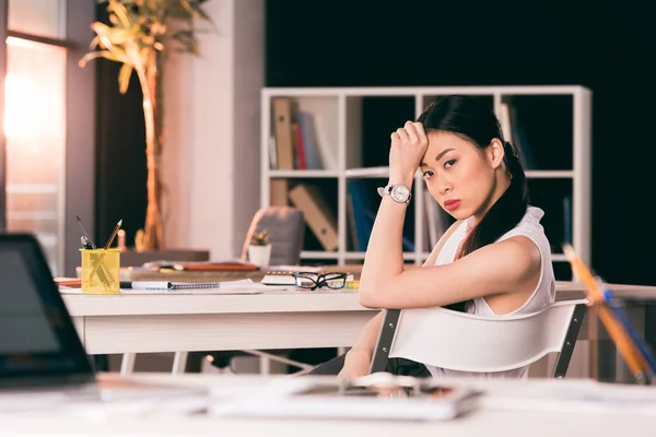 Nachdenkliche asiatische Geschäftsfrau sitzt am Tisch — Stockfoto