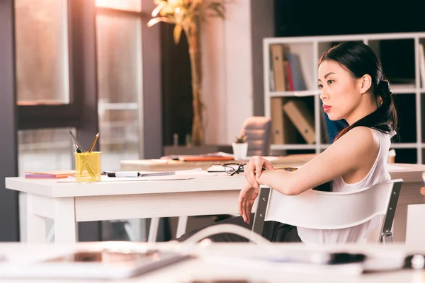 Asiática mujer de negocios sentado en oficina - foto de stock