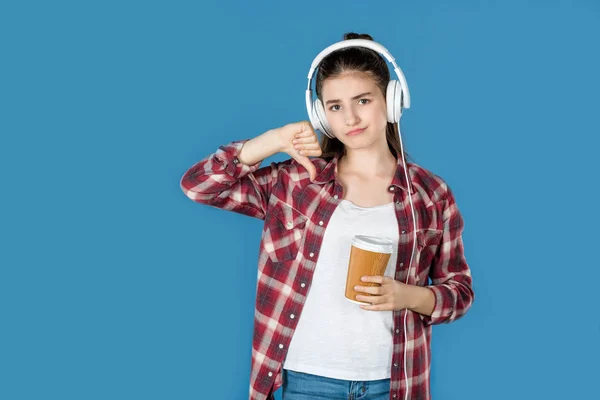 Chica en auriculares mostrando el pulgar hacia abajo - foto de stock