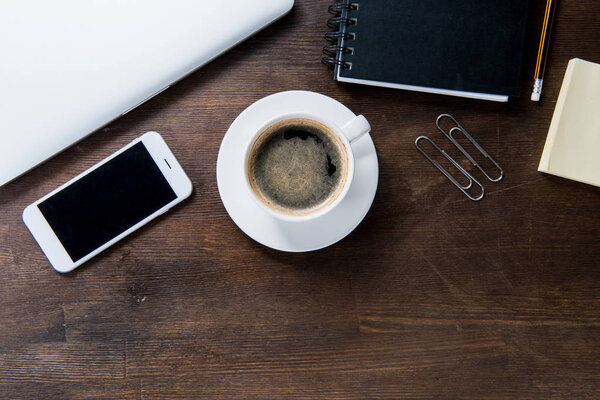Кофейная чашка и смартфон на столе
 