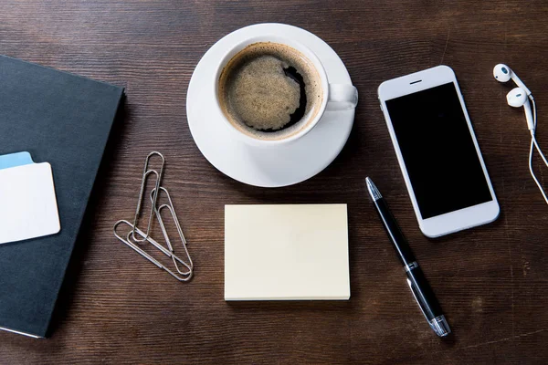 Kaffekopp och smartphone på skrivbord — Stockfoto