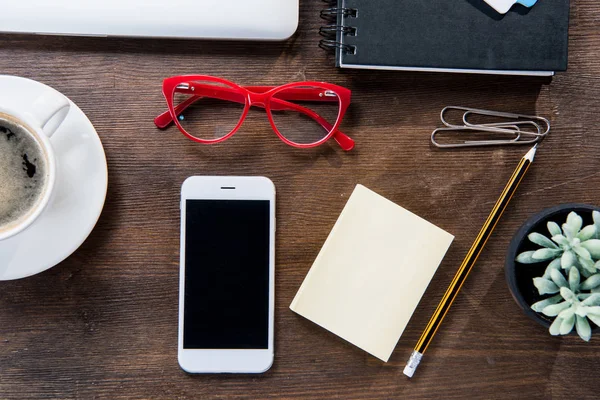 Kaffekopp och smartphone på skrivbord — Stockfoto