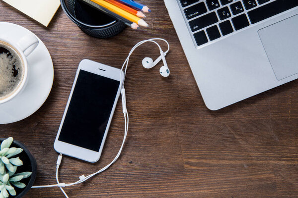 Кофейная чашка и смартфон на столе
 