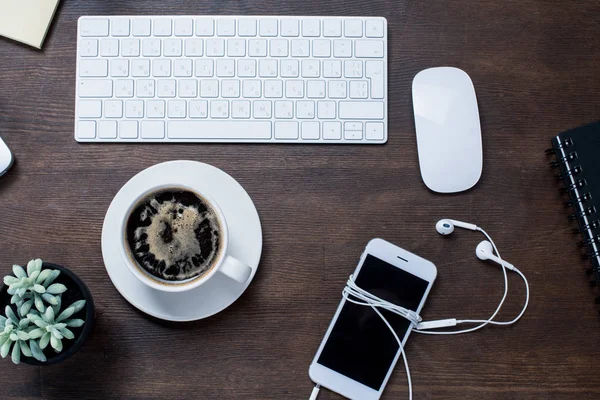 Кофейная чашка и смартфон на столе — стоковое фото