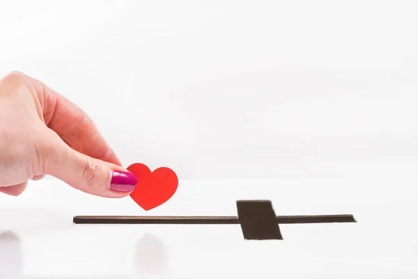 Hand inserting heart into hole for donations — Stock Photo, Image