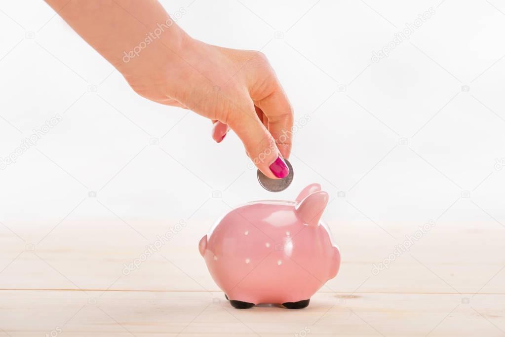 Hand putting coin in piggy bank 