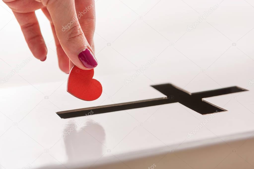 Hand inserting heart into hole for donations 