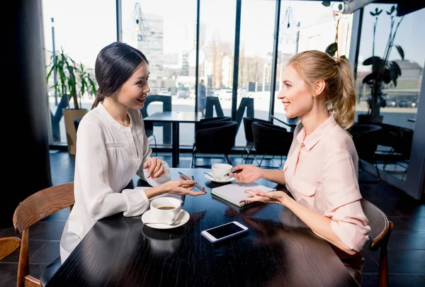 Young women drinking coffee and discussing — Stock Photo, Image