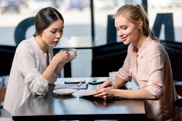 Junge Frauen trinken Kaffee und diskutieren — Stockfoto