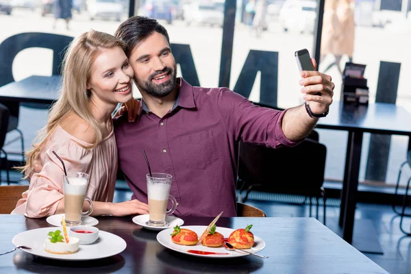 Влюбленная пара делает селфи на смартфоне — стоковое фото