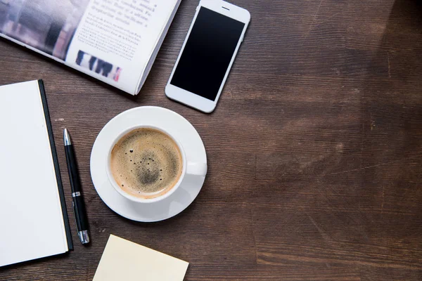 Taza de café y smartphone en el escritorio - foto de stock