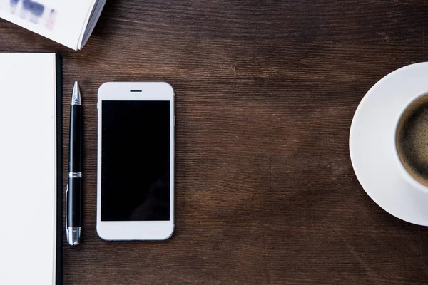 Coffee cup and smartphone on desk — Stock Photo