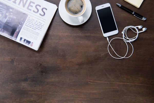 Coffee cup and smartphone on desk — Stock Photo