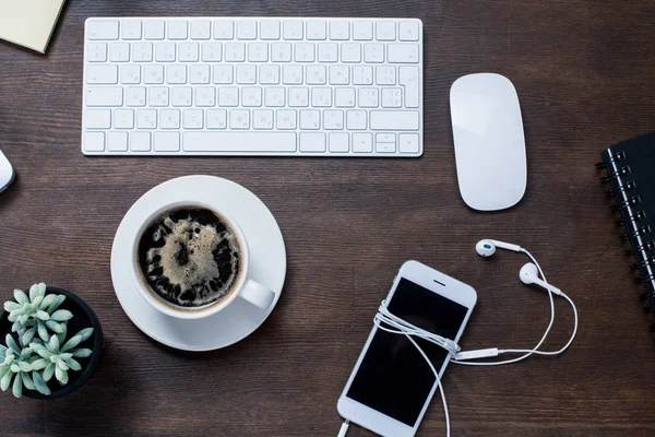 Coffee cup and smartphone on desk — Stock Photo