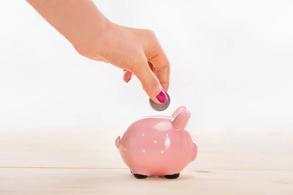 Mano poniendo moneda en alcancía - foto de stock