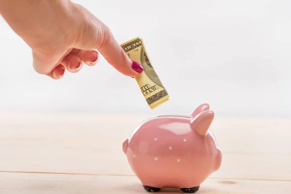 Hand putting banknote in piggy bank — Stock Photo