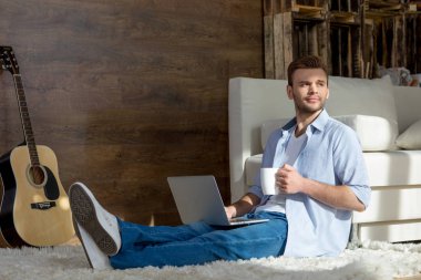 Young man with laptop and cup clipart