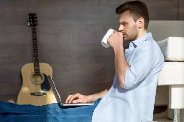Young man with laptop and cup clipart