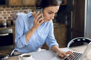 Dizüstü bilgisayar ve akıllı telefon kullanan kadın