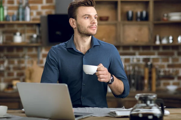 Άνθρωπος πίνει καφέ και χρησιμοποιώντας φορητό υπολογιστή — Φωτογραφία Αρχείου