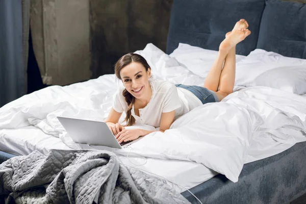 Kvinna som använder laptop i sängen — Stockfoto