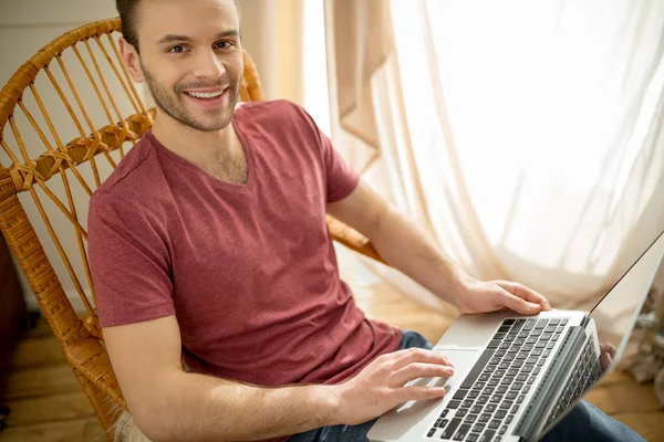 Homme avec ordinateur portable dans une chaise berçante — Photo de stock