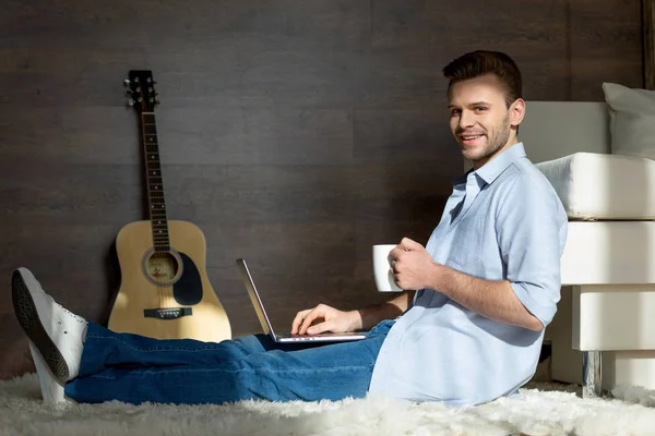 Joven con portátil y taza - foto de stock