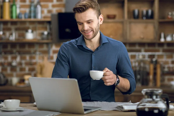 Homem bebendo café e usando laptop — Fotografia de Stock